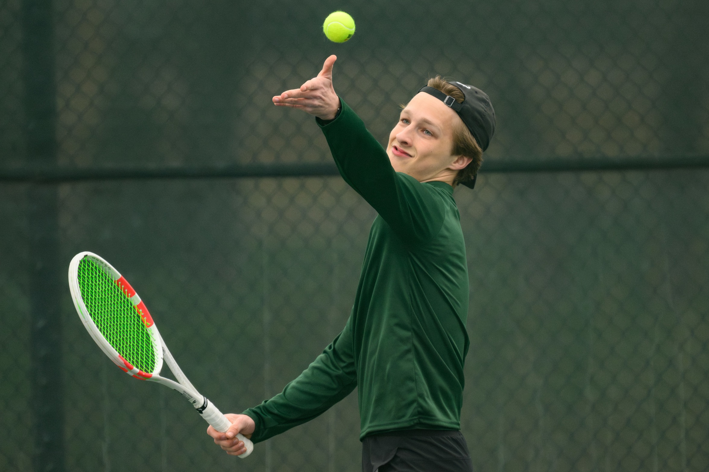 A Moraine Valley tennis player throws up a ball to serve.