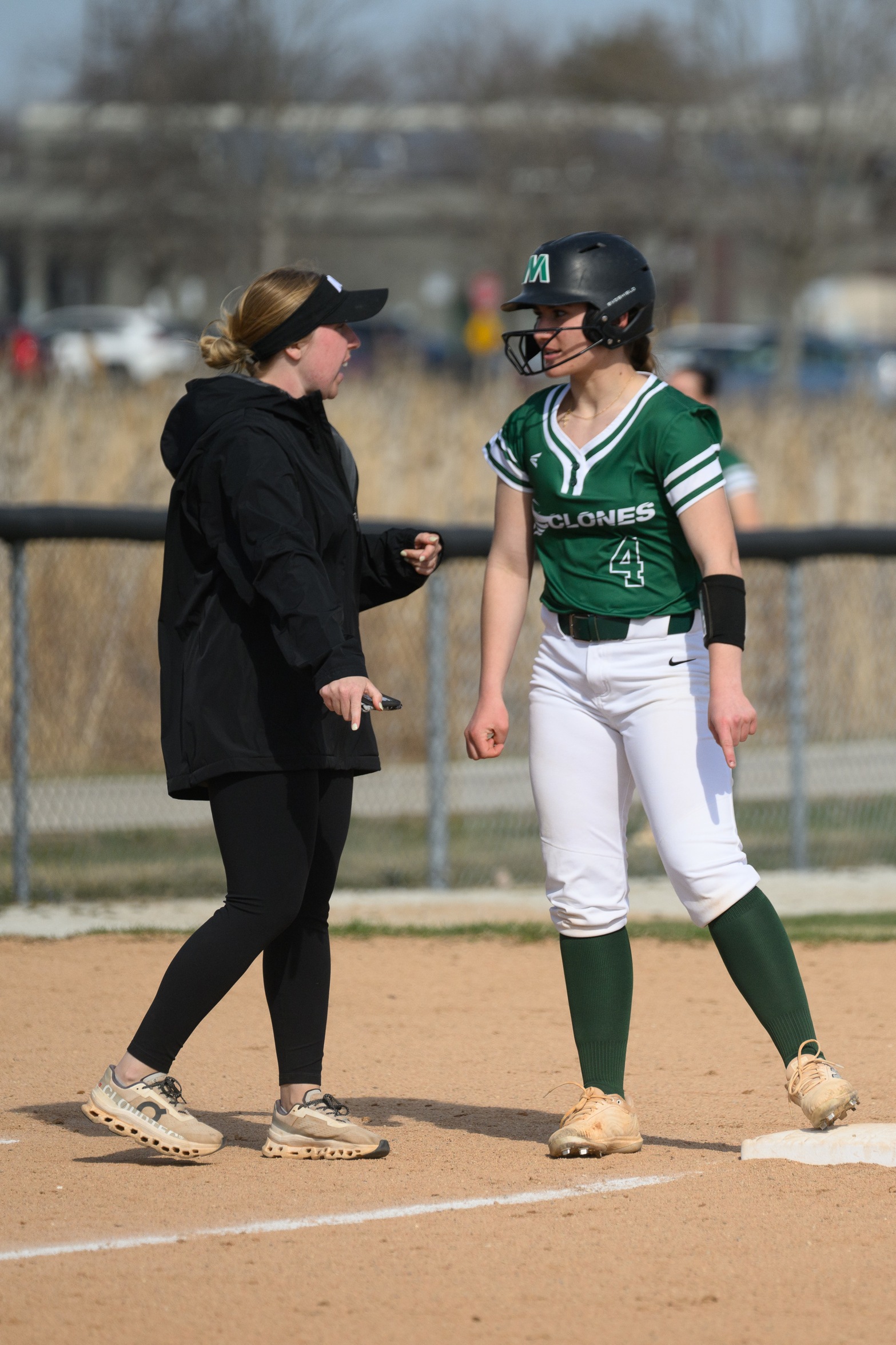Coach Megan Quinn talks to softball player Brooklynn Sedlak at third base.